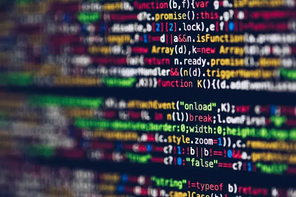 Colorful lines of computer code displayed on a screen. The code includes various functions, operators, and syntax highlighting in shades of red, green, blue, and yellow against a dark background.